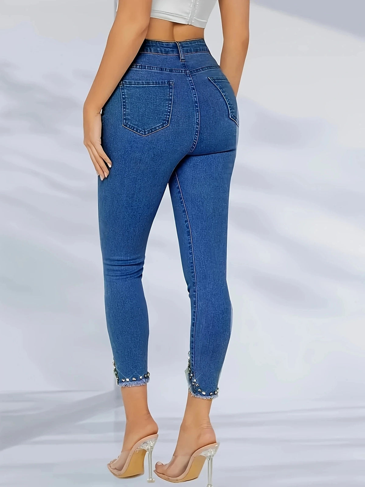High-waisted fashionable straight-leg jean with irregular hem and frayed edges; sequin-studded skinny jeans